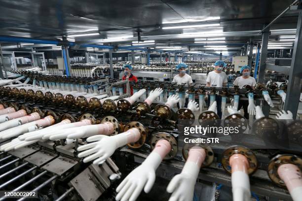 Workers produce medical gloves at a factory in Huaibei in China's eastern Anhui province on March 23, 2020. / China OUT