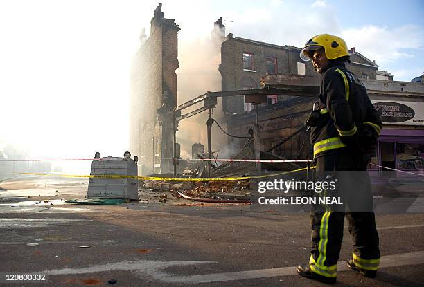 Fireman stands near a burnt-out pub on High Road in Tottenham, north London on August 7, 2011. Two police cars and a large number of buildings were...