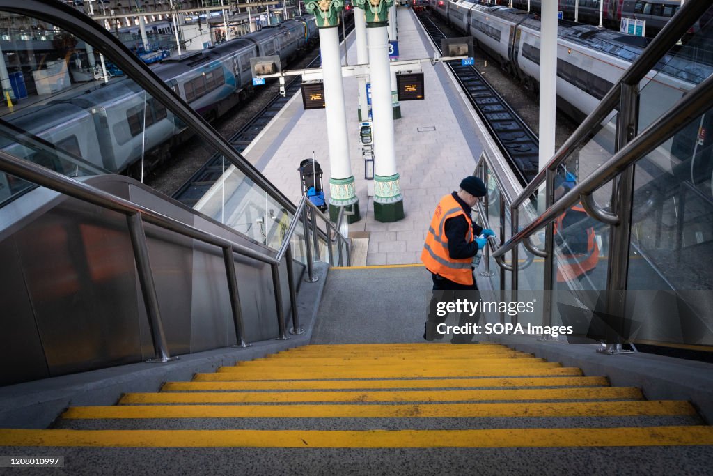 A cleaner wears a a face mask as a precaution against the...