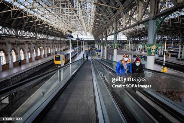 Two people wearing face masks as preventive measure against the COVID-19 coronavirus walk through a rather empty Piccadilly train station. Household...