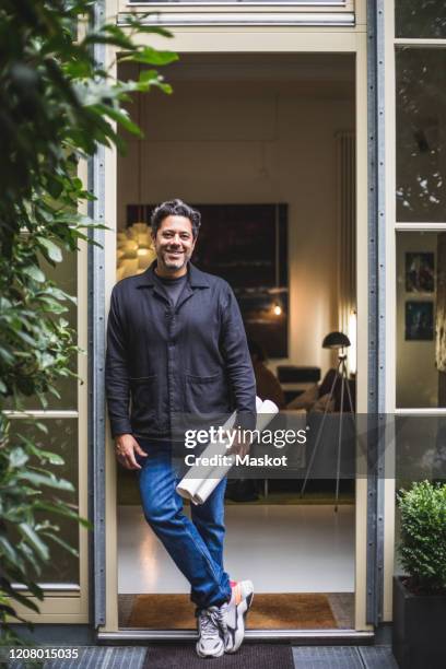 portrait of smiling mature architect with blueprint standing in doorway - entry draft portraits bildbanksfoton och bilder