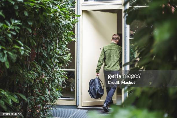 male entrepreneur with bag entering in house - entering stock pictures, royalty-free photos & images
