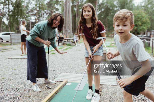 sibling playing miniature golf with family in backyard during vacation - mini golf stock pictures, royalty-free photos & images