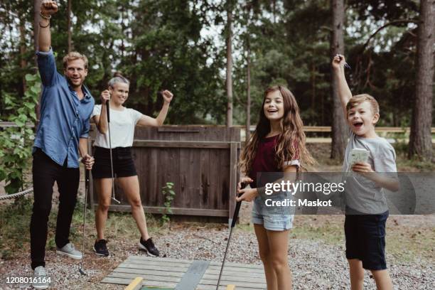 cheerful family with arms raised playing miniature golf in backyard - mini golf stock pictures, royalty-free photos & images