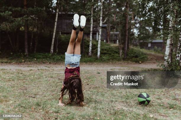 full length of girl doing handstand in forest - handstand fotografías e imágenes de stock