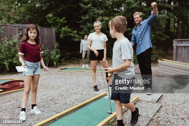 full length of family playing miniature golf in backyard - mini golf stock pictures, royalty-free photos & images