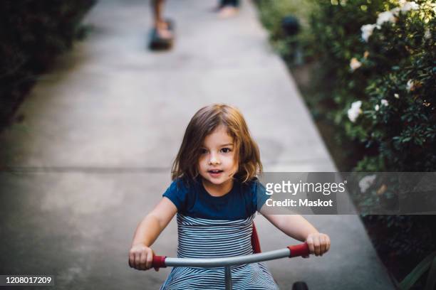 girl riding tricycle on footpath - tricycle stock pictures, royalty-free photos & images