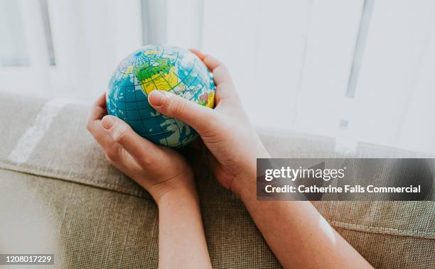 childs hands around a globe - united nations goals stock pictures, royalty-free photos & images