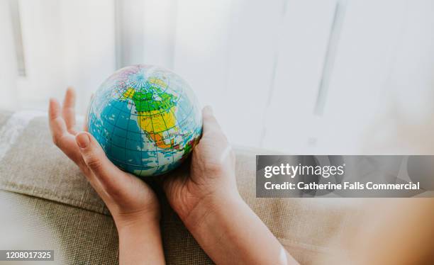 childs hands around a globe - onu stock pictures, royalty-free photos & images