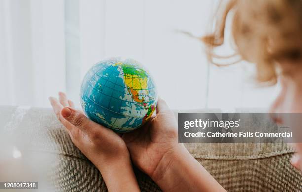 childs hands around a globe - united nations goals stock pictures, royalty-free photos & images