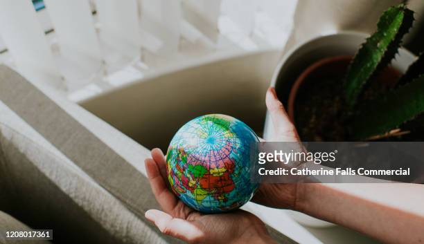 childs hands around a globe - united nations goals stock pictures, royalty-free photos & images