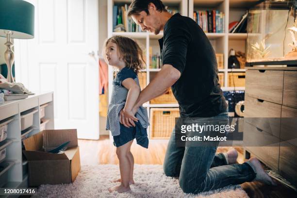 father dressing daughter in living room - kids dressing up stock-fotos und bilder