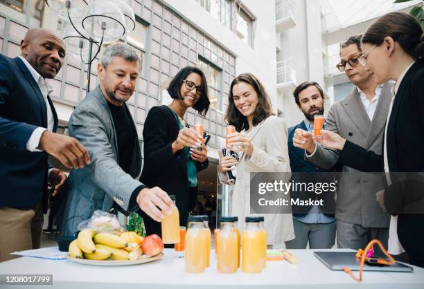 smiling male and female business executives with juice outside office - businessperson breakfast stock-fotos und bilder