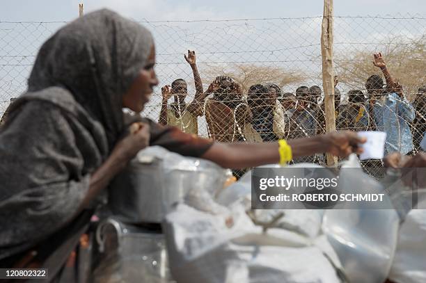 Newly arrived Somali refugees watch on July 06, 2011 from behind a fence outside a registration and food distribution center in Dadaab a woman who...