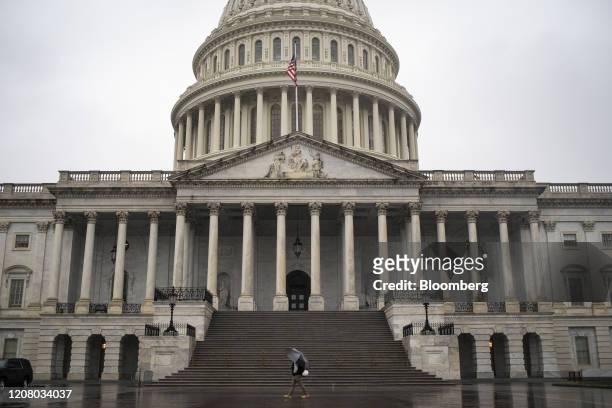 Man walks through the rain past the U.S. Capitol in Washington, D.C., U.S., on Monday, March 23, 2020. U.S. Senators in both political parties...