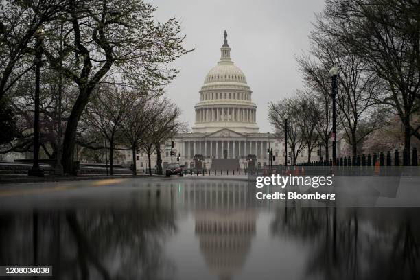 The U.S. Capitol is reflected in a pool of rain water on Capitol Hill in Washington, D.C., U.S., on Monday, March 23, 2020. U.S. Senators in both...