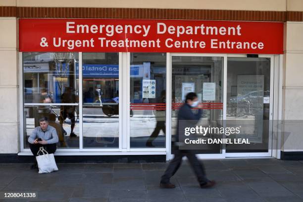 Man wearing a protective face mask walks past the Emergency Department and Urgent Treatment Centre entrance to Chelsea and Westminster hospital in...