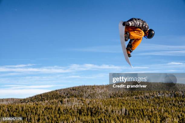 a young male snowboarder coming off a jump at a ski area in colorado on a sunny day - snowboard jump close up stock pictures, royalty-free photos & images