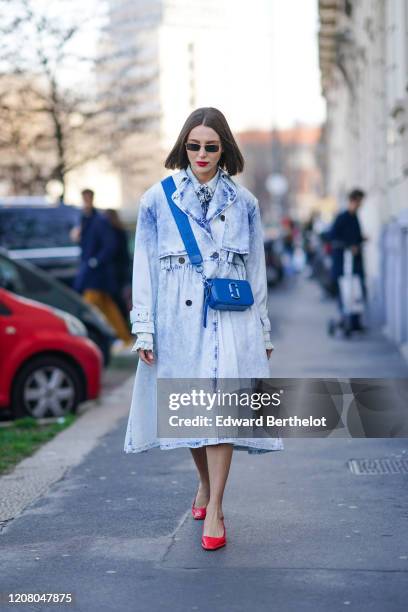 Mary Leest wears sunglasses, a pale blue denim dress, a Chloe bag, red pointy leather shoes, outside MSGM, during Milan Fashion Week Fall/Winter...