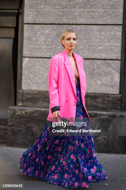 Leonie Hanne wears a blue ruffled dress with pink floral print, a black Jacquemus mini bag, a neon pink oversized blazer jacket, outside Philosophy,...