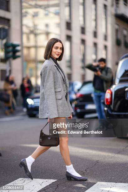 Mary Leest wears a gray oversized jacket, a Prada bag, white socks, pointy shoes, a tie, outside Ermanno Scervino, during Milan Fashion Week...