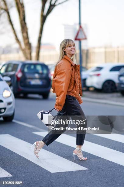 Jeanette Madsen wears a brown leather jacket, a Prada white and black bag, black leather pants, white shoes, outside MSGM, during Milan Fashion Week...