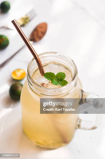 calamondin or philippine lime juice on a white wooden table - calamansi stock-fotos und bilder