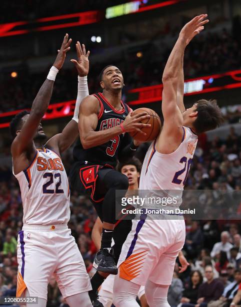 Shaquille Harrison of the Chicago Bulls puts up a shot between Deandre Ayton and Dario Saric of the Phoenix Suns at the United Center on February 22,...