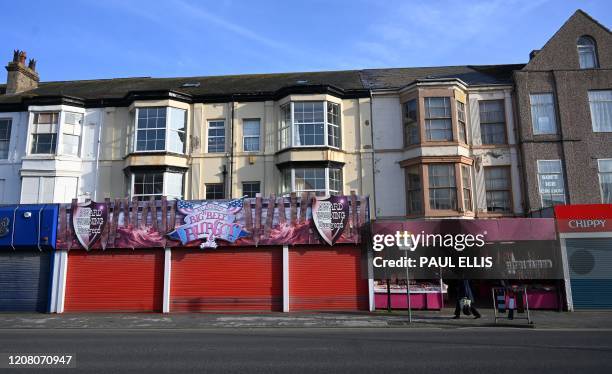 Woman walks past a "Rock Shop" in Rhyl, north Wales on March 23, 2020. - Prime Minister Boris Johnson warned on Sunday he may impose tougher controls...