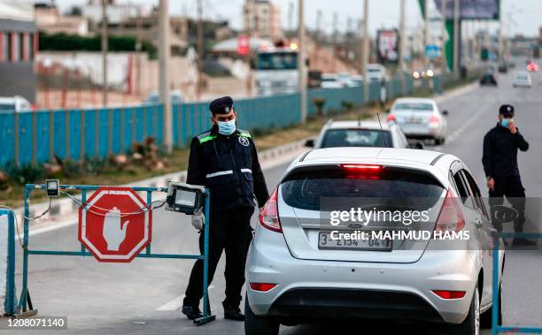 Palestinian policemen loyal to Hamas stop vehicles as they man a security checkpoint at the entrance of Gaza City on March 23, 2020.