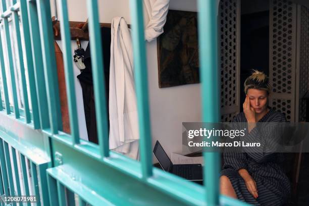 An American art dealer who has just woken up is seen through the grates of her balcony on March 22, 2020 in Rome, Italy. As Italy extends its...