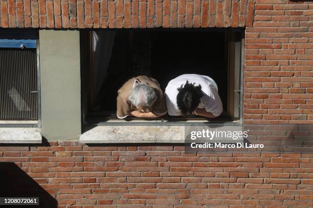 An elderly woman and her caregiver lean out of the window to watch what is going on in the street during lockdown on March 23, 2020 in Rome, Italy....