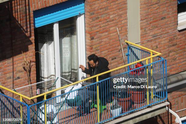 Man plays with his son and cell phone while smoking a cigarette on his balcony during lockdown on March 23, 2020 in Rome, Italy. As Italy extends its...