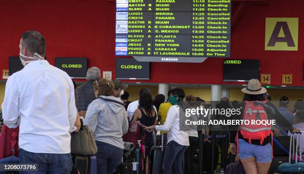 Stranded passengers line up looking for a flight to return to their countries, at Havana's Jose Marti airport, on March 23, 2020. - As of Tuesday,...