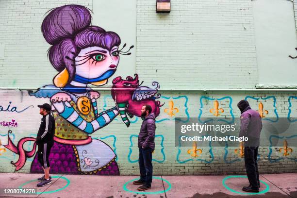 People stand in freshly painted circles, six-feet-apart, as they wait in a two-hour line to buy marijuana products from Good Chemistry on March 23,...