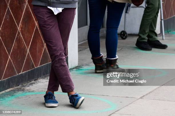 People stand in freshly painted circles, six-feet-apart, as they wait in a two-hour line to buy marijuana products from Good Chemistry on March 23,...