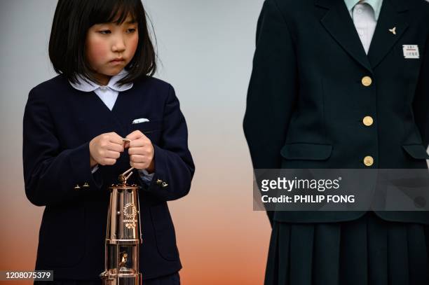 Primary school student holds the Tokyo 2020 Olympic flame as it goes on display to the public outside Fukushima railway station in Fukushima City on...