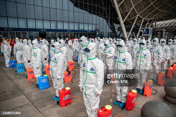 Staff members line up at attention as they prepare to spray disinfectant at Wuhan Railway Station in Wuhan in China's central Hubei province on March...