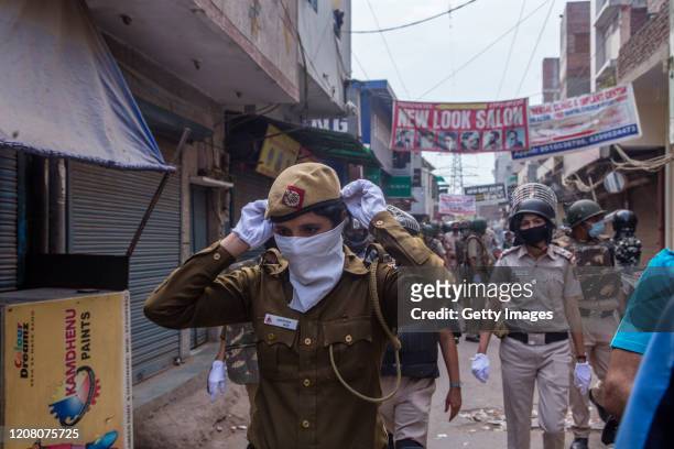 An Indian police woman adjusts her masks as she chases away protestors to vacate them from the protest demonstration sit, amid a nationwide lockdown...