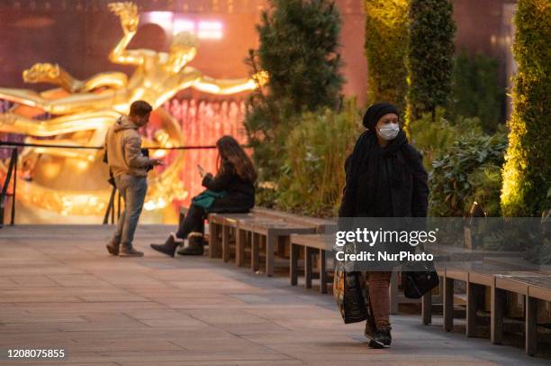 Woman wearing a facemark walks along Rockefeller Center Plaza on Friday, March 2020 in New York, NY. The city officially announced the closure of all...