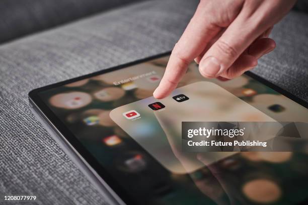 Detail of a mans hand pressing the Netflix app icon on an Apple iPad Pro tablet, taken on March 6, 2020.