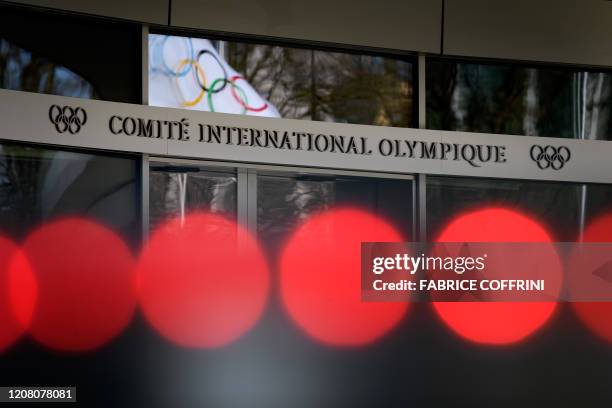 An Olympic flag is seen in window's reflection at the entrance of the headquarters of the International Olympic Committee in Lausanne on March 24,...