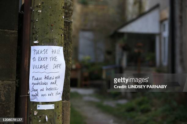 Sign on a lamp post asking people to stay at home and observe the guidelines on social distancing is seen in the village of Eyam in Derbyshire,...