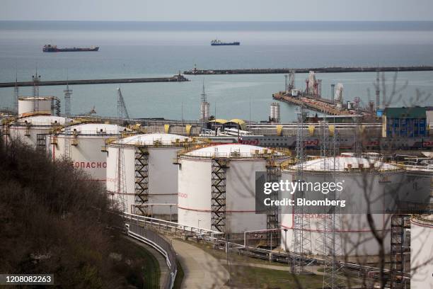 Oil storage tanks stand at the RN-Tuapsinsky refinery, operated by Rosneft Oil Co., as tankers sail beyond in Tuapse, Russia, on Monday, March 23,...