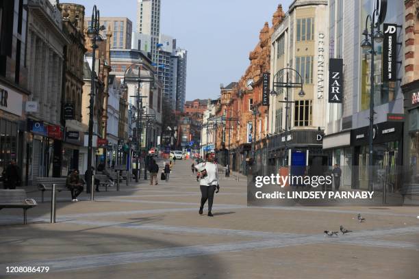 Woman walks along a deserted city centre shopping street in Leeds, northern England, on March 24, 2020 after Britain ordered a lockdown to slow the...