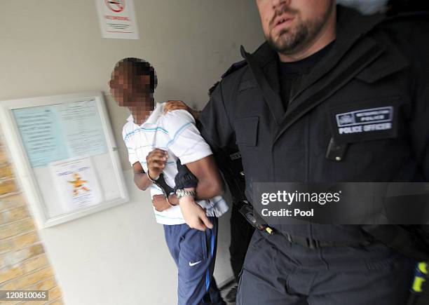 Metropolitan Police officers arrest a man suspected of involvement in the riots after carrying out a raid on a property on the Churchill Gardens...