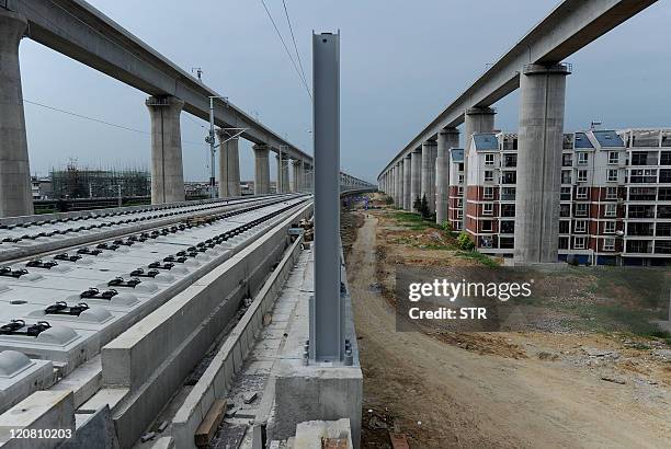 This photo taken on August 10, 2011 shows residential buildings sitting between concrete supports of a high-speed train line in Shuandun county, in...