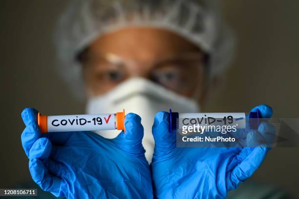 Woman in protective suit, respirator and glasses holding test tubes with sample of analysis infected and uninfected with coronavirus COVID-19 in...