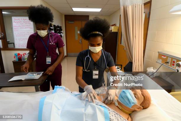 Student nurses Nicole Obisie and Nazarine Beweh attend to a patient caremanikin in a training simulation at an education lab of the License Practical...