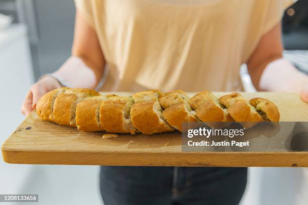 woman holding wooden board with garlic bread - garlic bread stockfoto's en -beelden